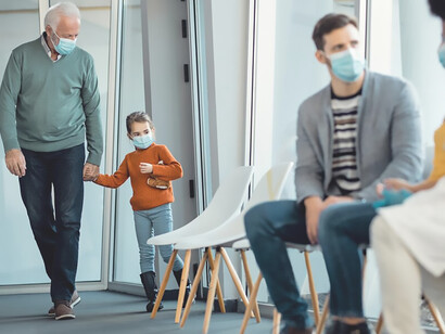 Senior man holding hands with granddaughter while coming at medical clinic during coronavirus pandemic