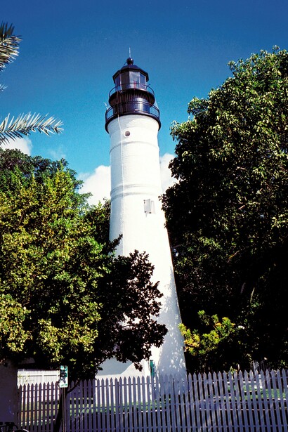 The Key West Lighthouse above the treetops in Key West, Florida, symbolizing the spirit of a destination where history and literature meet