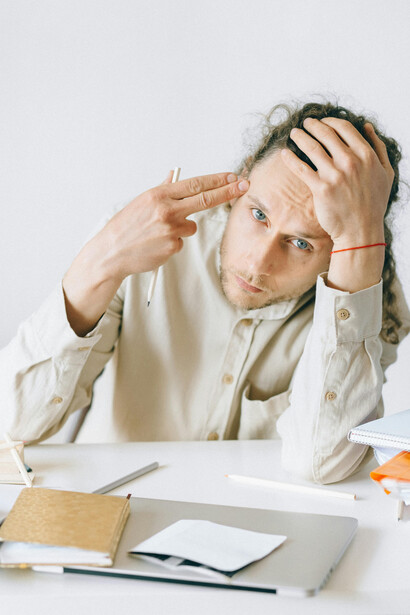 Young office worker experiencing stress and mental exhaustion at his desk, highlighting workplace burnout and anxiety among Gen-Z professionals