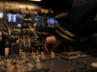 A pilot operating the controls of an aircraft cockpit, representing the balance between human judgment and increasingly automated technologies