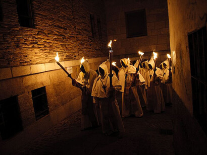 Semana Santa en León. Hermanos de una cofradía recorren la ciudad iluminando la calle con sus velas