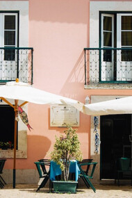 Adoring Lisbon's charms, two white patio umbrellas grace a pink and white painted building, Portugal