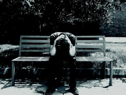 Un hombre triste en el banco de un parque