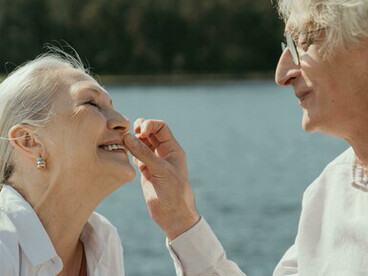 Happy elderly couple smiling together by the lake