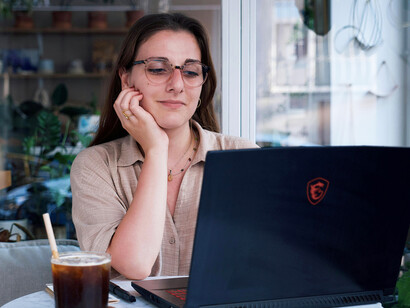 Young woman sitting at a café table using a laptop