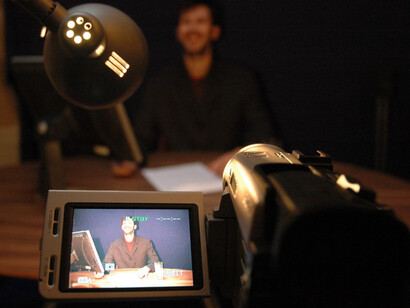 A real news anchor shown on the viewer of the camera
