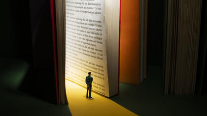 Small human figure reading it in the light hitting the huge book