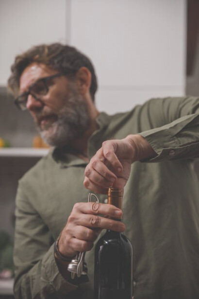 A man skillfully removes the wine cap from the bottle