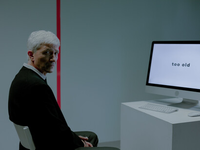 A man stares sadly while a computer displays a rejection message