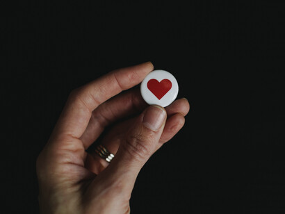 Una mano sostiene un 'pin' de un corazón