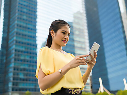 An Asian woman checking her messages outdoors