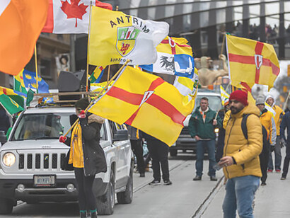 Capturing the spirit of Saint Patrick's Day, a man takes a lively selfie amidst a group proudly parading with County Antrim flags