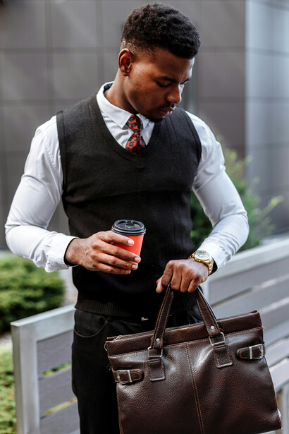 A man in business casual attire holds a cup of coffee