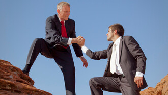 Un hombre ayuda a otro a subir un risco. El líder humilde valora el trabajo y éxito de los demás por encima del suyo