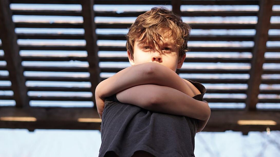 A young boy hugging himself