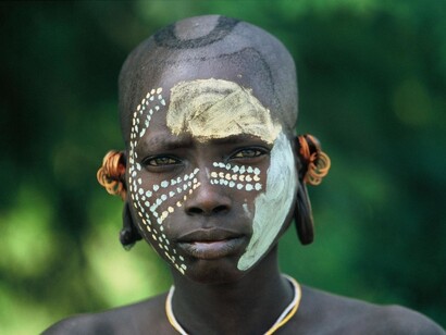 A Mursi boy with a ritual's mask on
