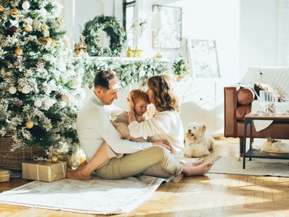 A happy family sitting together on a rug beside a traditional Christmas tree