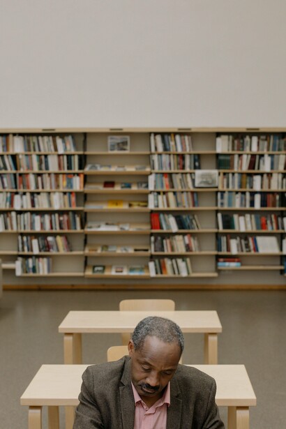 A person sat in front of some bookshelves in a library