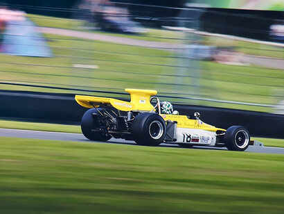 A yellow race car driving down a race track