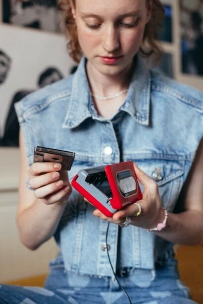 Teenage girl sitting on her bed, holding a stack of cassette tapes