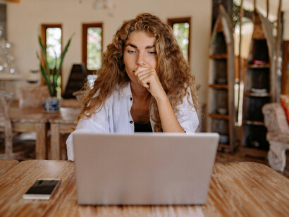 Escritorio con una notebook y un celular. En estos dispositivos se utilizan voces femeninas para los asistentes virtuales