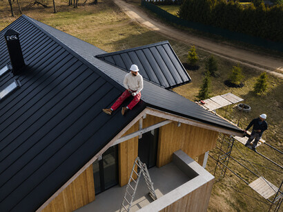 Roofers wearing helmets work together on a portable house