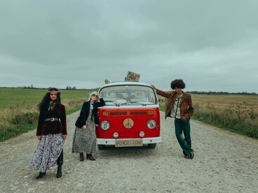 A group of young people gathered beside a red Volkswagen van, suggesting nostalgia and freedom