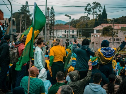 A large Brazilian flag rising above a public gathering, symbolizing the strong sense of national identity influencing the election
