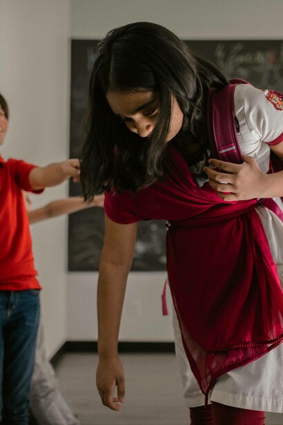 Young girl lowers her gaze as she walks away from bullies