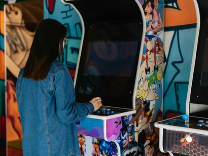 A young woman playing an old arcade game, representing the revival of old-school entertainment