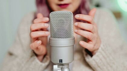 A woman placing her hand on a microphone