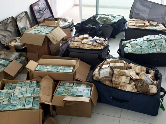 Malas e caixas com parte dos R$ 51 milhões em dinheiro vivo apreendidos pela Polícia Federal em um apartamento atribuído ao ex-ministro Geddel Vieira Lima (do partido MDB), em Salvador (BA), em 2017. O imóvel ficou conhecido como "bunker do Geddel" e se tornou um dos maiores símbolos da corrupção e do desvio de recursos públicos na história recente do Brasil, embora tenham surgido novos casos como fraudes contra aposentados e pensionistas do INSS e os desdobramentos do caso Banco Master, que recolocaram corrupção, fiscalização e responsabilização no centro da agenda nacional