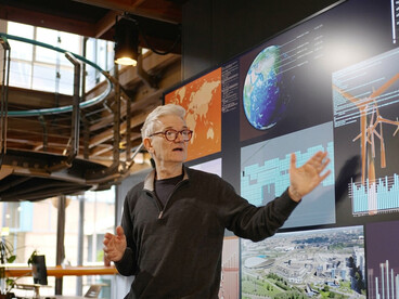 A speaker presents clean energy solutions on a large screen during a renewable energy seminar