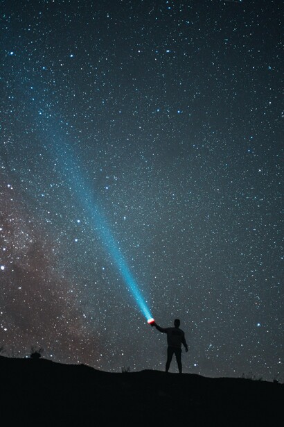 Sob a imensidão do universo, uma pequena luz humana rompe a escuridão. A literatura também nasce desse impulso de iluminar o desconhecido