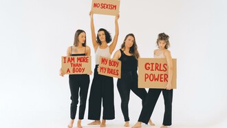 Mulheres de calças pretas segurando cartazes sobre o empoderamento feminino