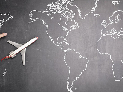 An artistic depiction of an airplane soaring over a world map on a blackboard 