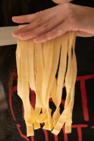 La résistance se savoure : dans La Pastasciutta antifascista, chaque geste compte. Ici, les bras d’une interprète révèlent les spaghettis fraîchement coupés, symbole d’un acte quotidien devenu acte de liberté et de partage