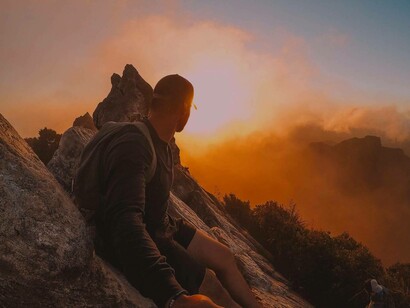 Un ragazzo si gode la vista dall'alto di una montagna: siate causa di quello che succede