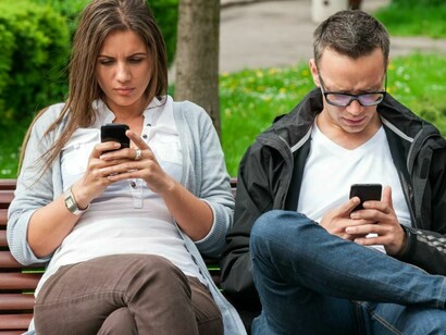 Una pareja mirando sus respectivos teléfonos móviles