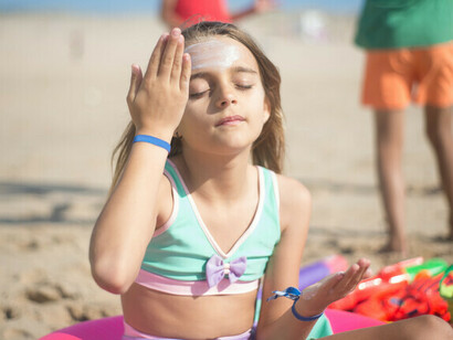 Una niña se frota protector solar en la cara