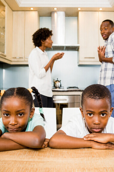 Children sit silently at the dinner table, listening to their parents argue