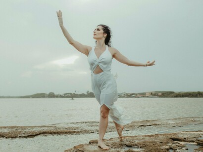 Bailarina na praia. E se, ao invés de resistir ao invisível, nos rendêssemos a ele? Se, ao invés de buscar fora, olhássemos para dentro? Essa rendição é um convite para nos tornarmos artistas da nossa própria vida, criando uma dança onde cada movimento, cada pausa e cada respiração se alinham com a perfeição divina que sempre esteve em nós
