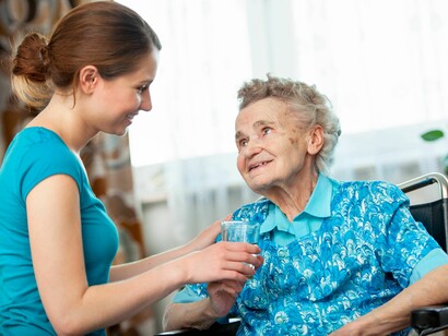Una cuidadora atiende a una anciana