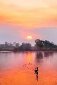 A man fishing on the Mekong River in Laos as the sun sets