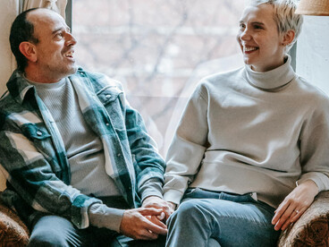 A happy couple sitting on a couch and talking together