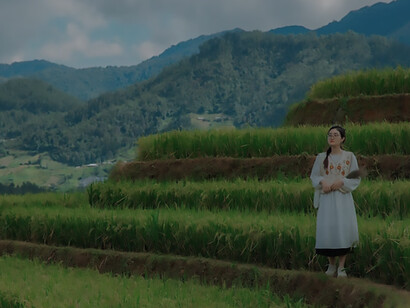 Surrounded by expansive layers of agricultural land, a woman becomes the embodiment of sustainable agriculture and the commitment to clean, wholesome food production