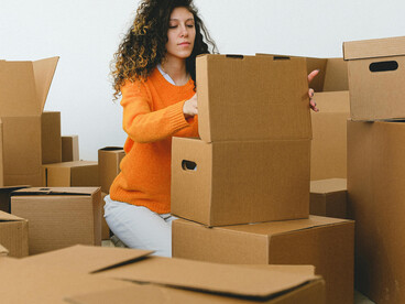 A young woman packs and arranges moving boxes as she begins a new chapter