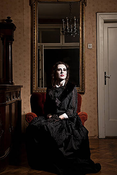A spectral woman appears next to an armchair, her image captured in an ornate Victorian mirror
