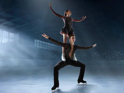 A figure skating couple performs on a quiet, empty rink, surrounded by the cold ambiance and focused spotlight