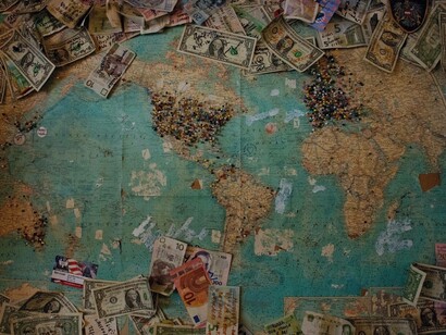 A map of the world and the multitude of currencies pinned and on display where the American dollar is featured in numerous places